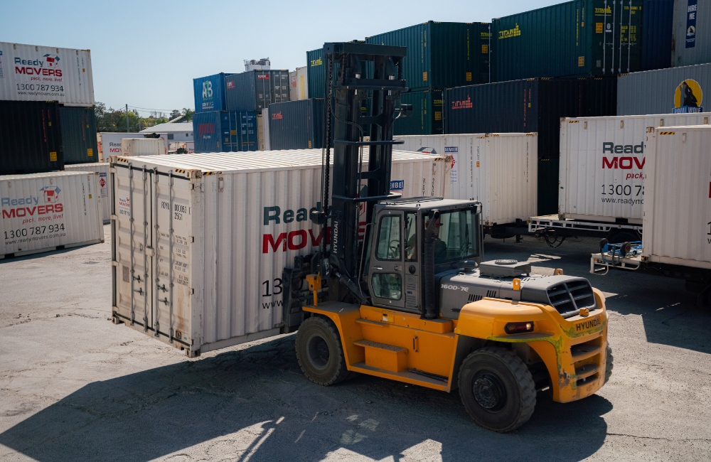 A forklift moving a Ready Movers shipping container.