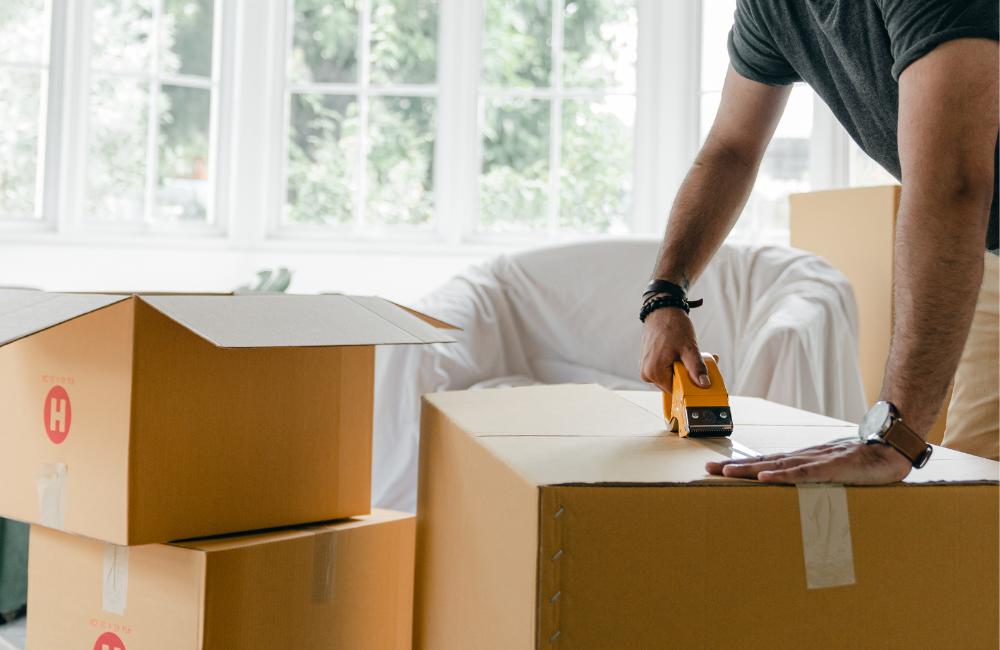 A man taping up a removalist box