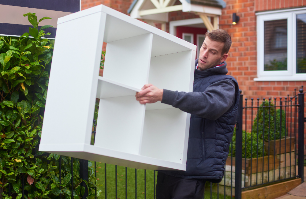 A man carrying a white four square shelf.